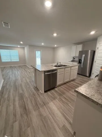 a large kitchen with stainless steel appliances granite countertop a lot of counter space and wooden floors