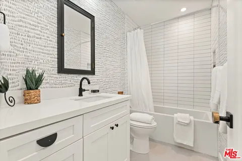 a bathroom with a granite countertop sink a toilet and a mirror