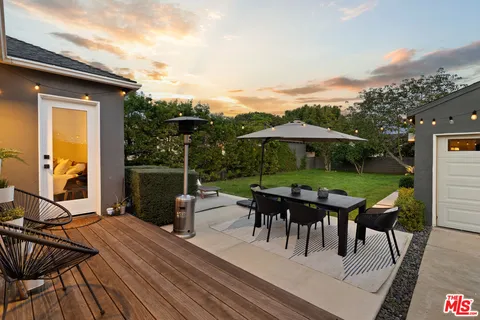 a view of a patio with table and chairs under an umbrella with wooden floor