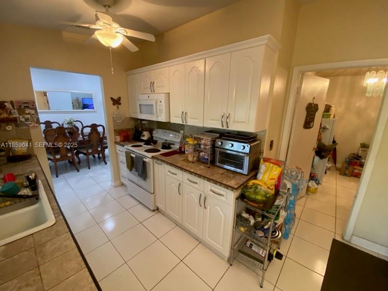 25931 Southwest 130th Avenue Homestead, FL 33032 - Photo 19 of 44 a kitchen with stainless steel appliances a sink a stove top oven a counter space and cabinets