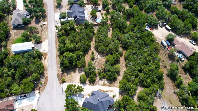 an aerial view of residential houses with outdoor space and trees all around