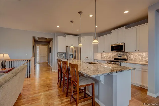 a kitchen with stainless steel appliances granite countertop a stove top oven a refrigerator a sink and a dining table with wooden floor