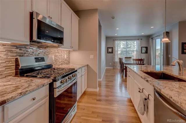 a kitchen with stainless steel appliances granite countertop a stove a sink and a microwave