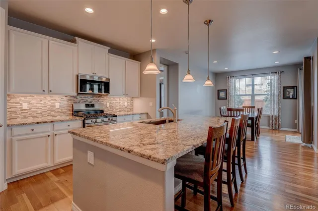 a kitchen with stainless steel appliances granite countertop a stove a sink a microwave a dining table and chairs