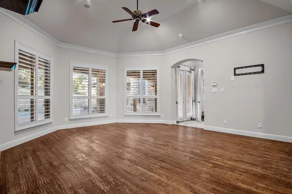 a view of an empty room with a window and wooden floor