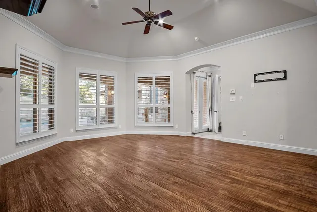 a view of an empty room with a window and wooden floor