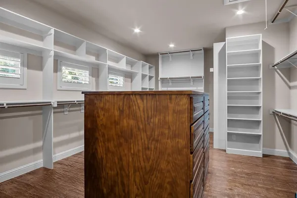 a view of walk in closet with wooden floor and windows