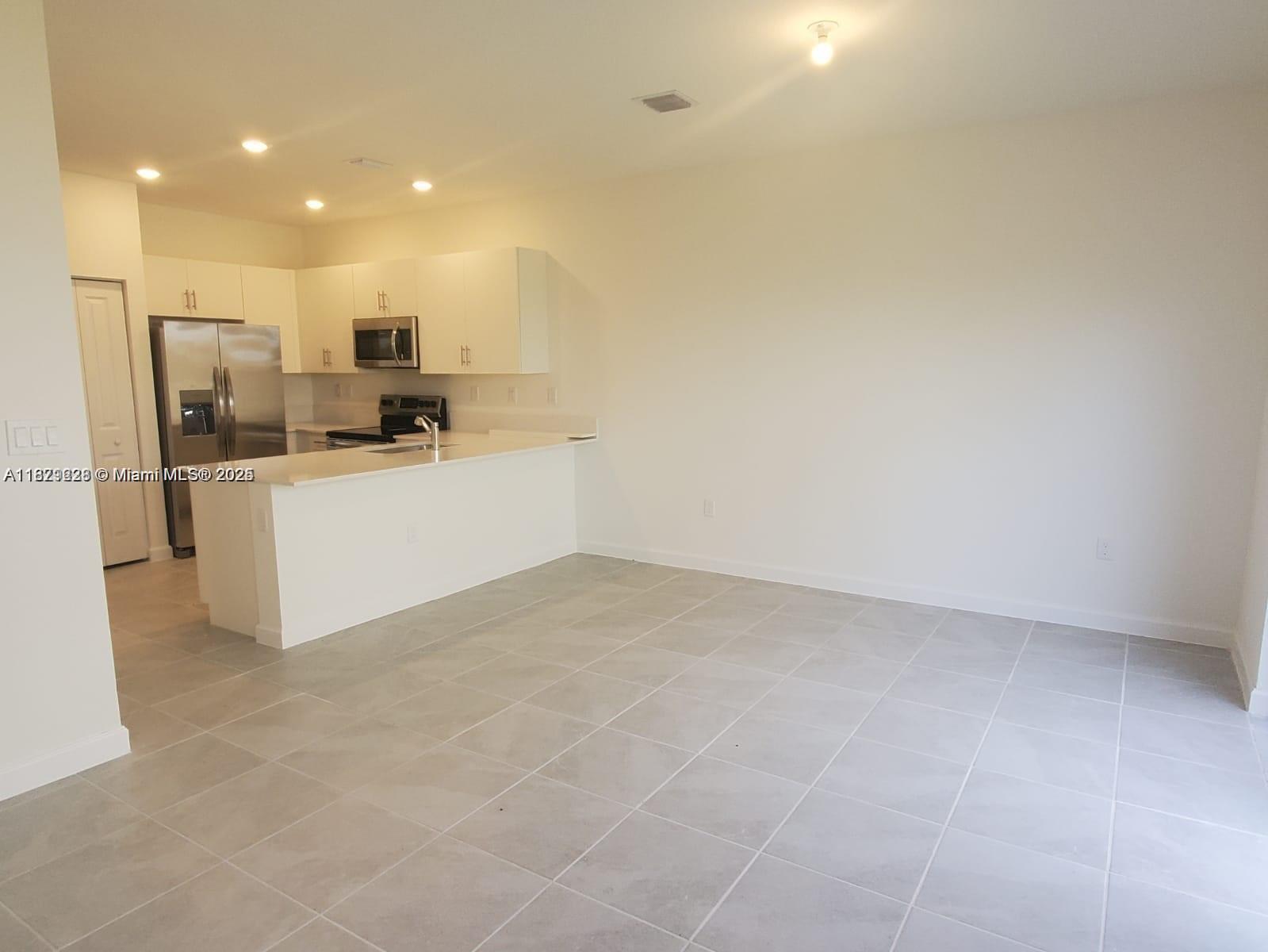 2602 Southeast 11th Street, Unit 2602 Homestead, FL 33035 - Photo 6 of 22 a kitchen with stainless steel appliances a refrigerator and a stove top oven