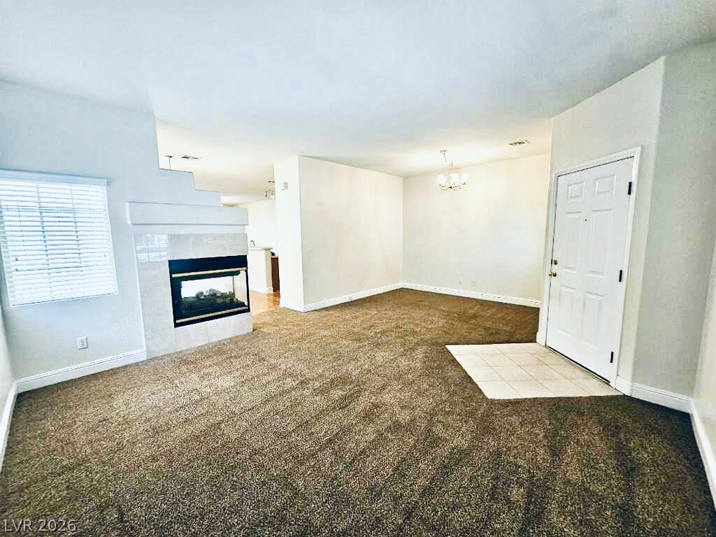 5953 Crumbling Ridge Street Henderson, NV 89011 - Photo 3 of 42 A welcoming entryway with a tile landing flows into a carpeted living space, anchored by a sleek fireplace.