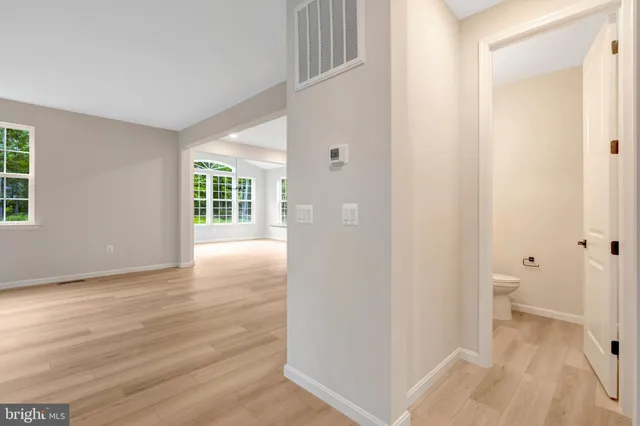 a view of a hallway with wooden floor and a bathroom