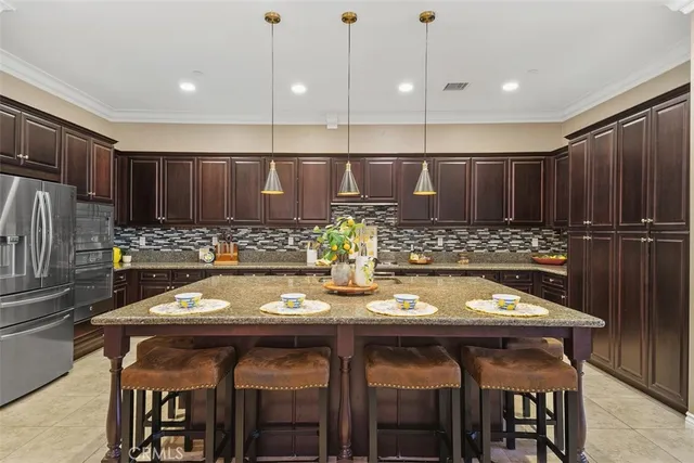 a kitchen with stainless steel appliances granite countertop a sink a stove and chairs