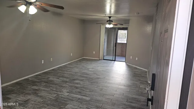 a view of an empty room with wooden floor and chandelier