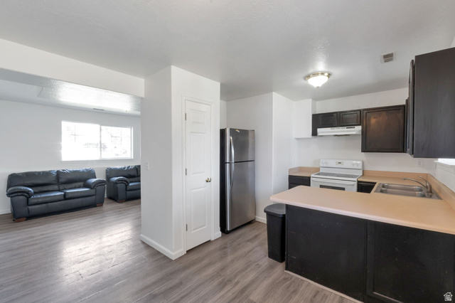 2013 West 460 South Provo, UT 84601 - Photo 21 of 24 Open-concept kitchen and living area featuring wood-finish flooring, dark cabinetry, light countertops, and stainless steel appliances