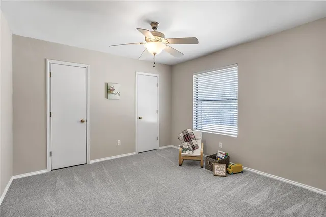 an empty room with windows and ceiling fan