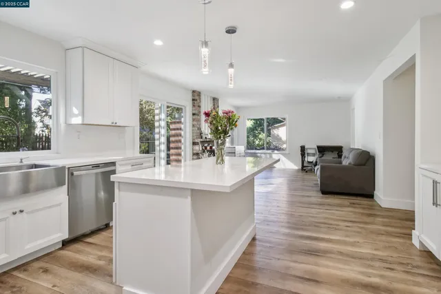 a kitchen with stainless steel appliances kitchen island granite countertop a sink and a wooden floors