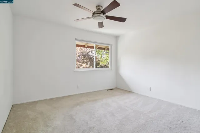 an empty room with a window and a fan