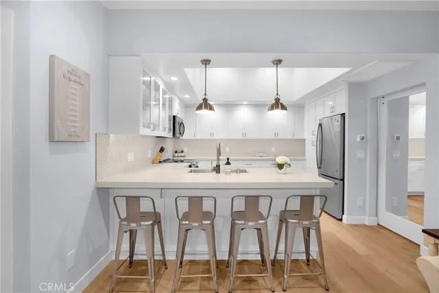 a kitchen with stainless steel appliances granite countertop a dining table chairs and white cabinets