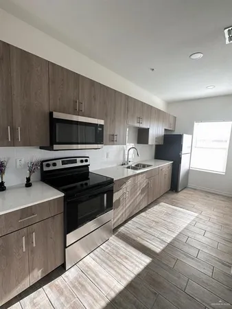 a kitchen with stainless steel appliances kitchen island granite countertop a sink dishwasher stove top oven and wooden cabinets