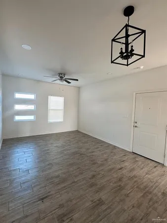 a view of a room with wooden floor ceiling fan and windows