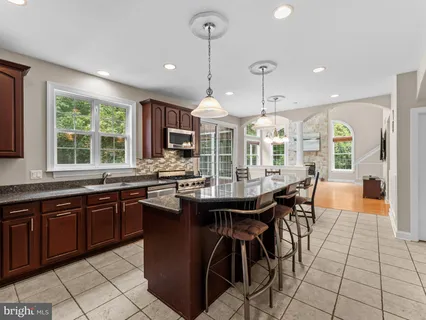 a kitchen with stainless steel appliances granite countertop a sink a stove a dining table and chairs with wooden floor