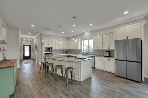 a kitchen with stainless steel appliances granite countertop a refrigerator a stove a sink dishwasher and a refrigerator with wooden floor