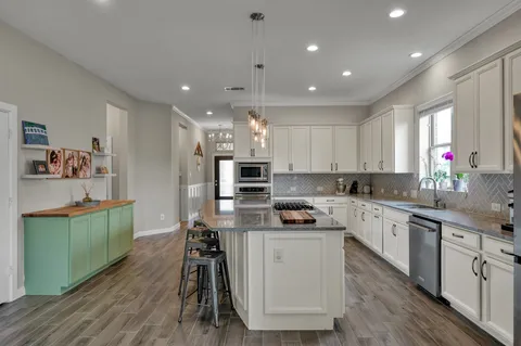 a kitchen with kitchen island white cabinets and stainless steel appliances