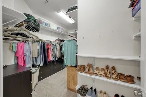 a view of walk in closet with clothes and shoes