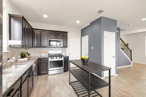 a kitchen with stainless steel appliances granite countertop a stove top oven a sink dishwasher and cabinets with wooden floor