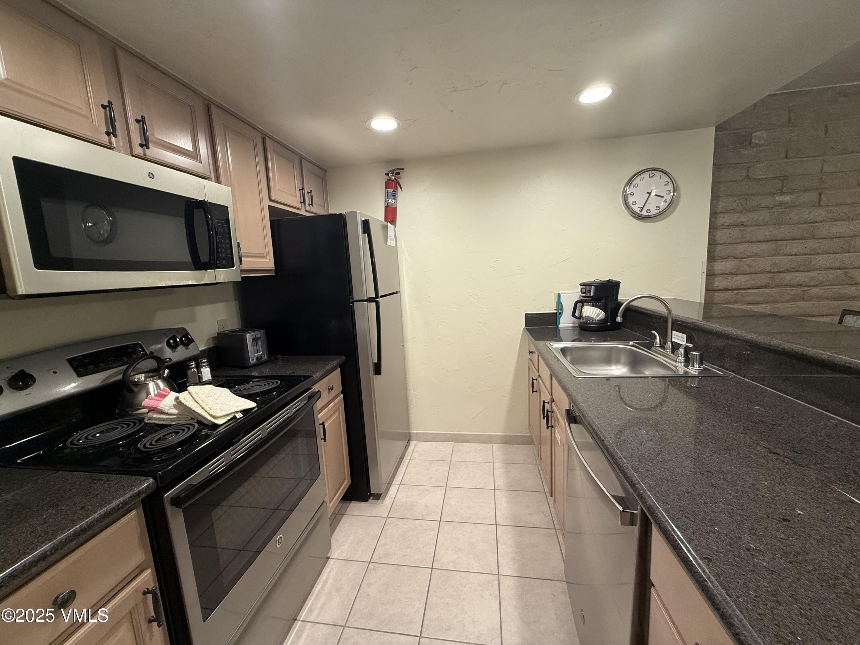 a kitchen with granite countertop a sink stove and refrigerator