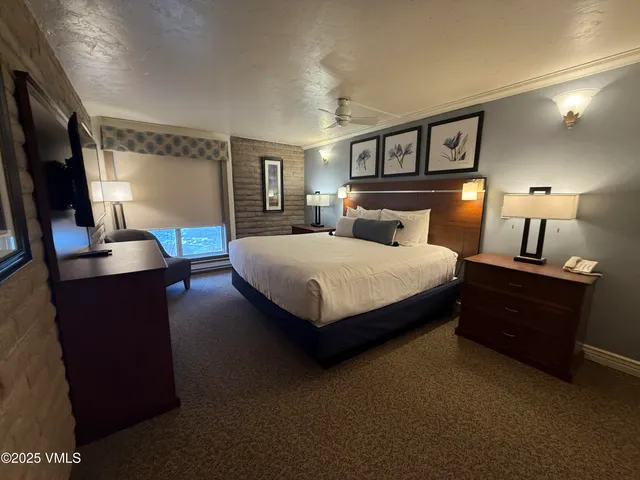 a bedroom with a bed lamps and a large mirror on the dresser