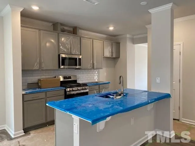 a kitchen with stainless steel appliances a stove a sink a microwave a refrigerator and cabinets