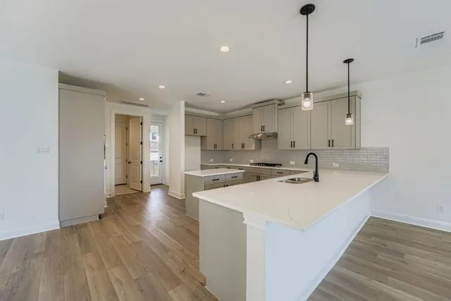 a kitchen with stainless steel appliances granite countertop a sink a oven a refrigerator and a wooden floor