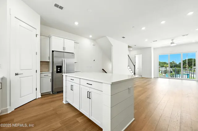 a kitchen with a refrigerator a sink and wooden floor
