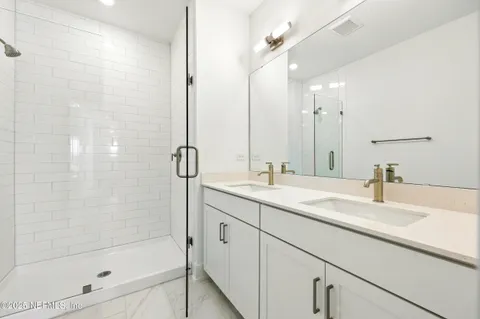 a bathroom with a bathtub shower sink vanity and mirror