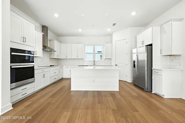 a large kitchen with stainless steel appliances cabinets and a wooden floor