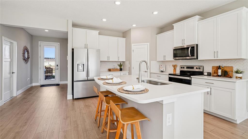 4265 Southwest 52nd Lane Road Ocala, FL 34474 - Photo 6 of 40 a kitchen with stainless steel appliances kitchen island granite countertop a refrigerator a stove a sink and white cabinets with wooden floor
