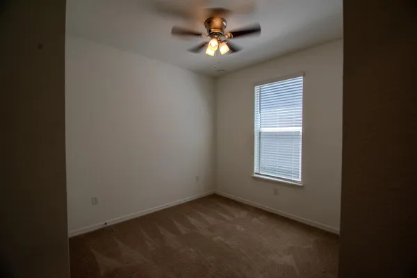 an empty room with a window and a fan