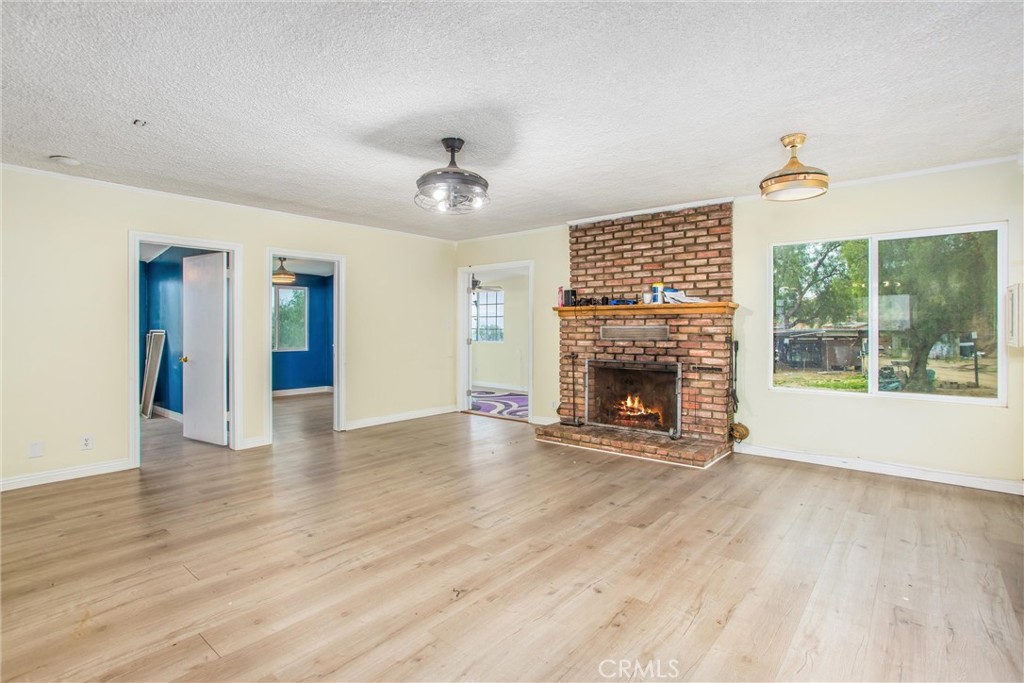 23255 Warren Road San Jacinto, CA 92582 - Photo 29 of 56 a view of an empty room with wooden floor fireplace and a window