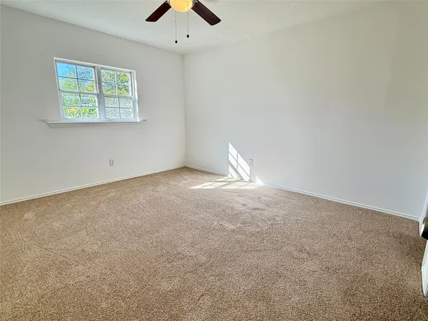 an empty room with a window and a fan