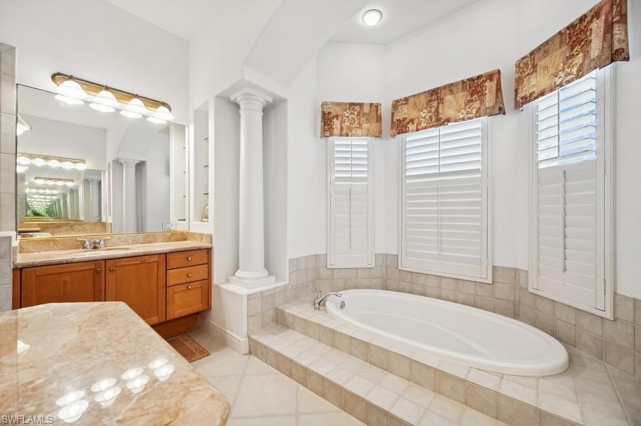 7488 Treeline Drive Naples, FL 34119 - Photo 13 of 22 Bathroom with ornate columns, a garden tub, vanity, and tile patterned floors