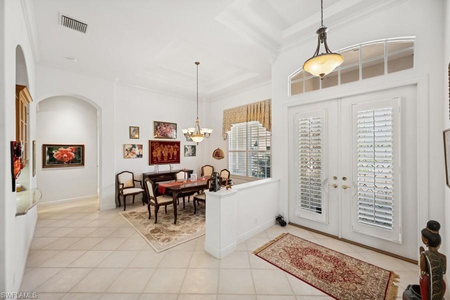 7488 Treeline Drive Naples, FL 34119 - Photo 5 of 22 Foyer entrance featuring arched walkways, ornamental molding, light tile patterned floors, french doors, and a chandelier