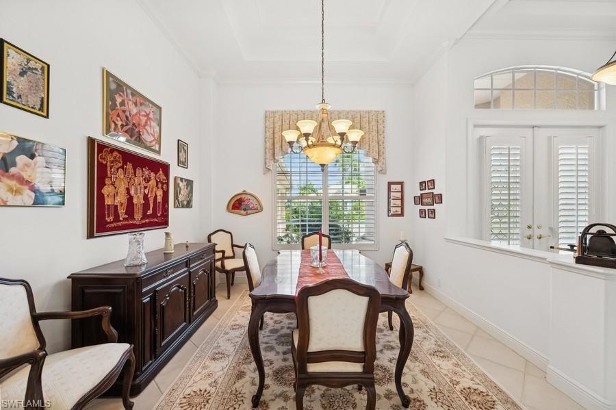7488 Treeline Drive Naples, FL 34119 - Photo 7 of 22 Dining space featuring a chandelier, plenty of natural light, light tile patterned floors, a tray ceiling, and crown molding