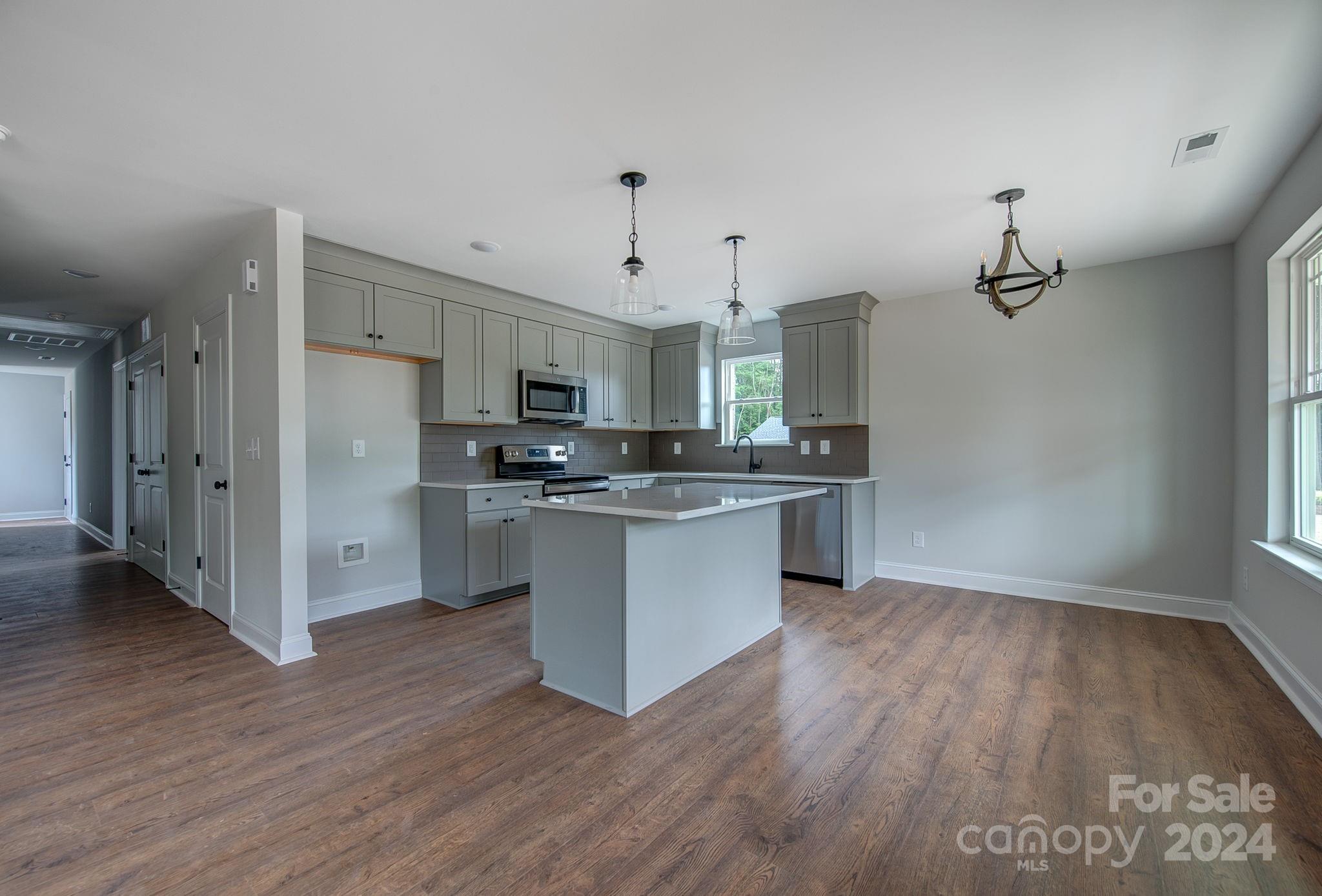 527 Blacksnake Road Stanley, NC 28164 - Photo 11 of 22 a kitchen with stainless steel appliances kitchen island wooden floors and white cabinets