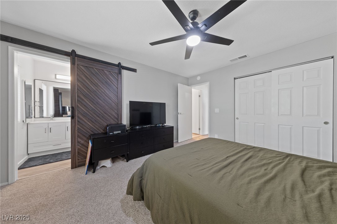 2637 Rialto Road Las Vegas, NV 89108 - Photo 13 of 22 Bedroom with carpet, a closet, visible vents, ensuite bathroom, and a barn door