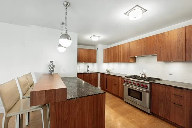 a kitchen with stainless steel appliances granite countertop a stove a sink dishwasher and a refrigerator with wooden cabinets