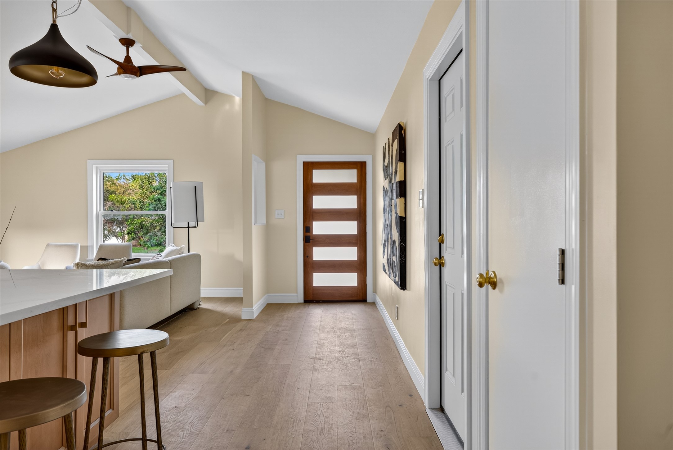 6806 Rearden Road Austin, TX 78745 - Photo 9 of 28 Vaulted ceilings with exposed beams, wood-finish flooring, and a modern entry door with frosted glass panels