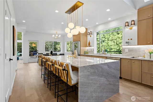 an open kitchen with granite countertop a stove a sink a dining table and chairs with wooden floor