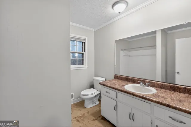 a bathroom with a granite countertop sink a toilet and a mirror