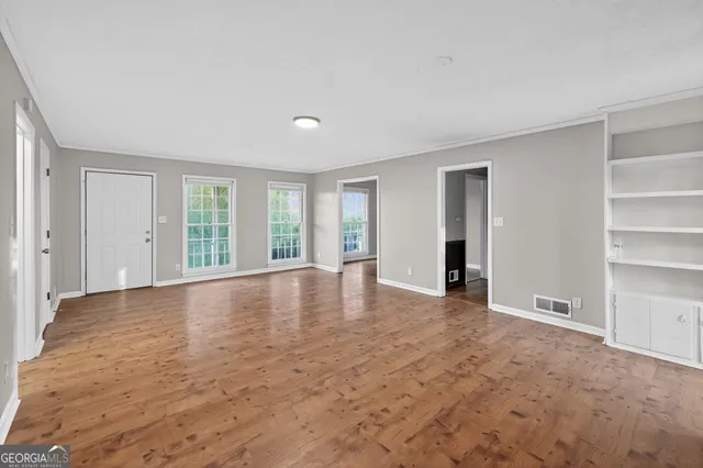 a view of an empty room with a window and wooden floor