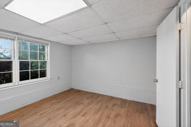 an empty room with wooden floor and windows